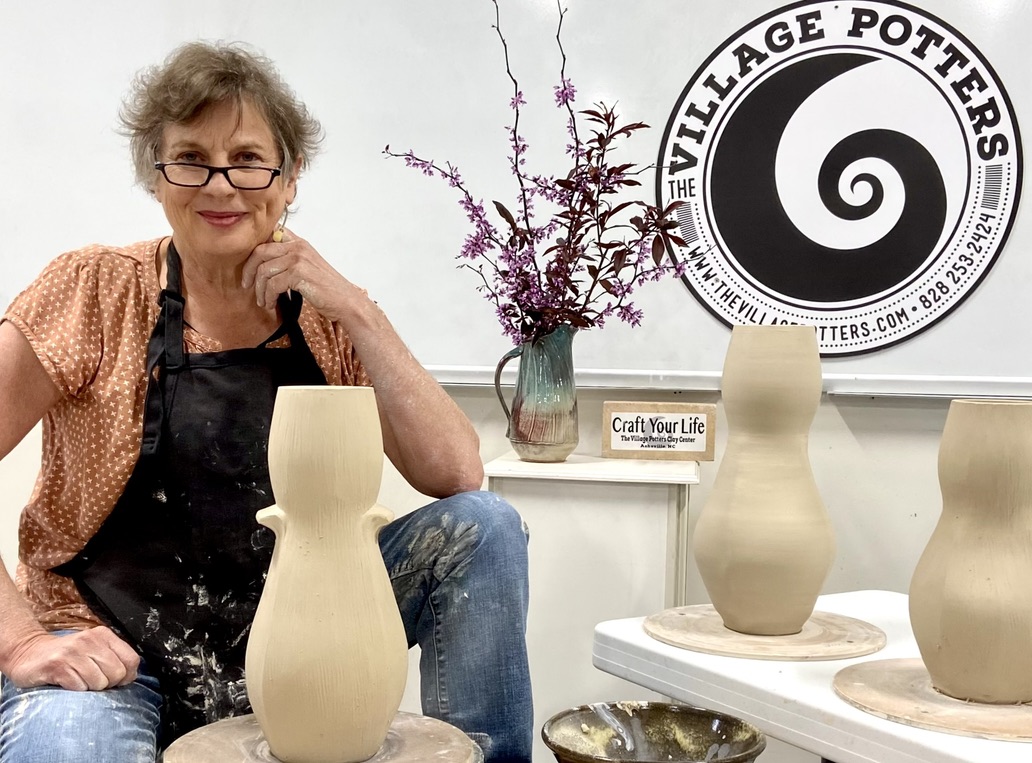 Sarah Wells Rolland sitting with leather hard vases with TVP circular logo