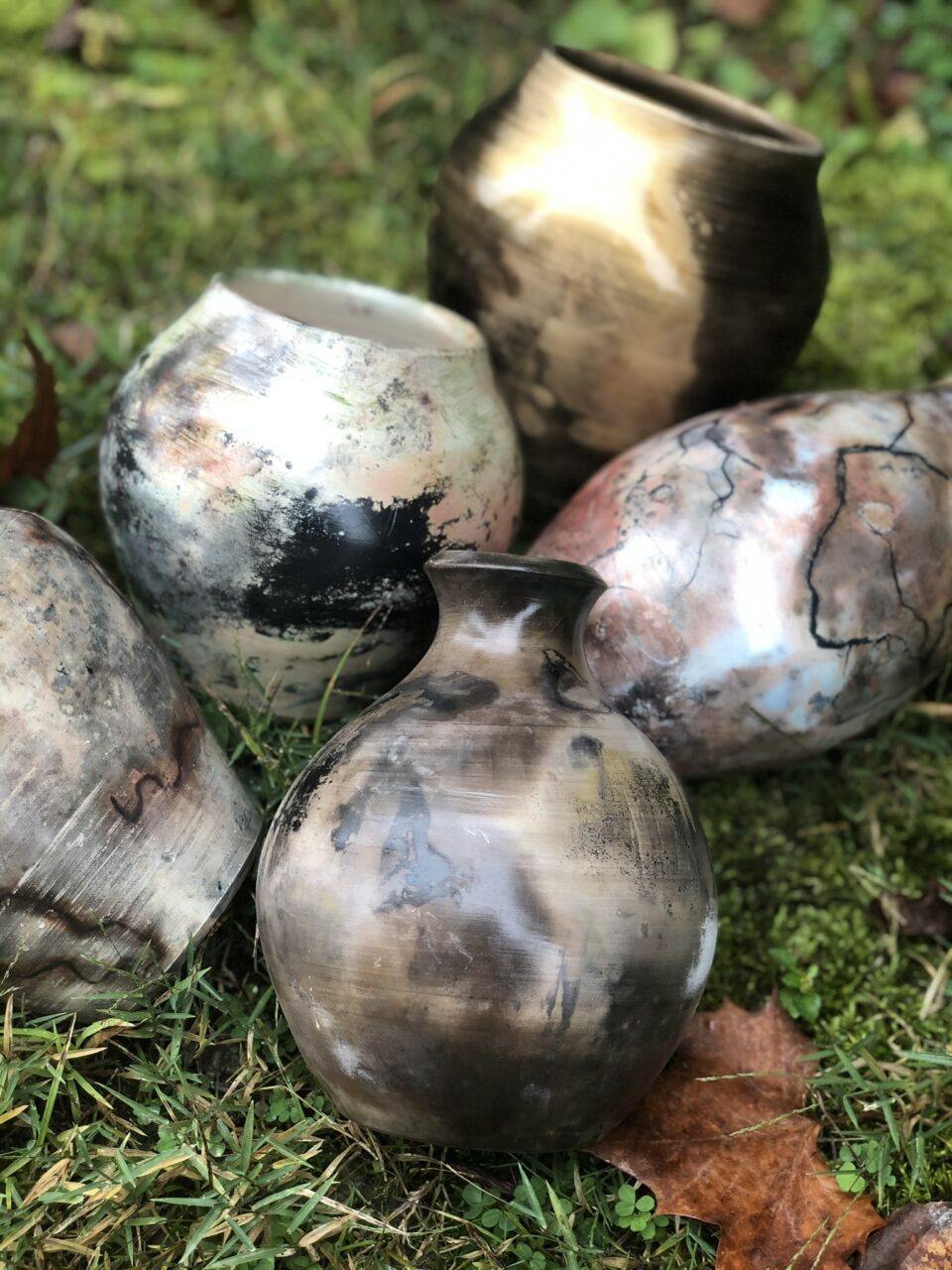 Judi Harwood grouping of finished pots, small sagger pots in the grass