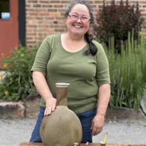 Karen Dubois standing with grouping of her finished pots, wood soda kazie pots, large vase