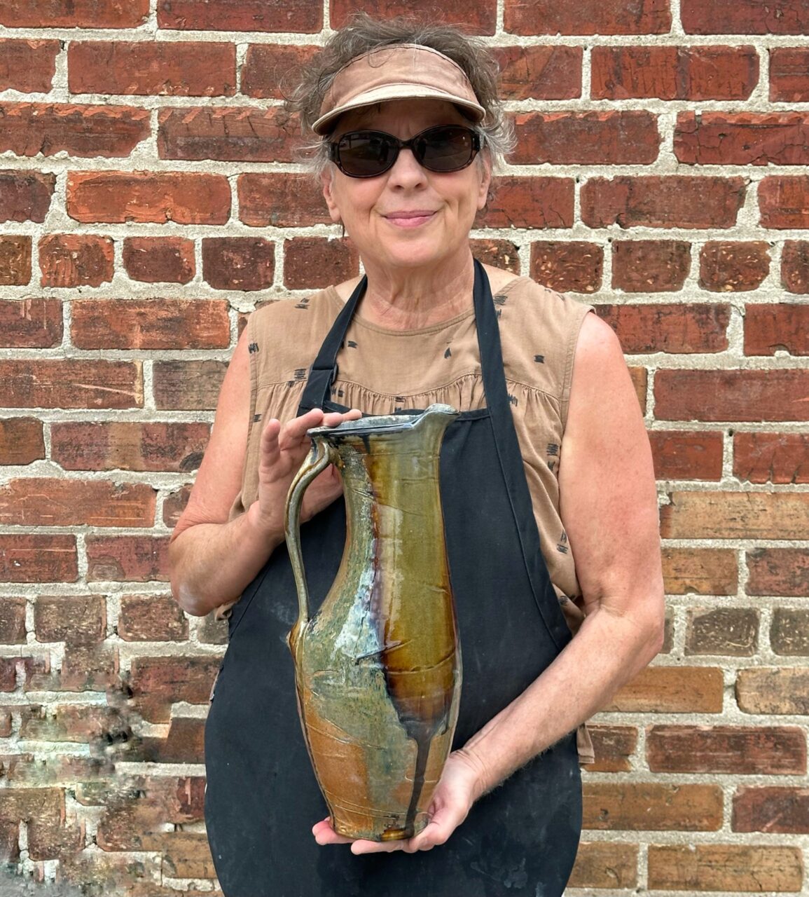 Sarah Wells Rolland holding finished pot, wood soda kazie pitcher