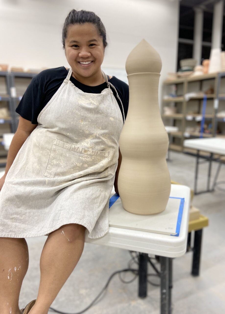 Katie Meili Messersmith sitting next to leather hard sectional pot