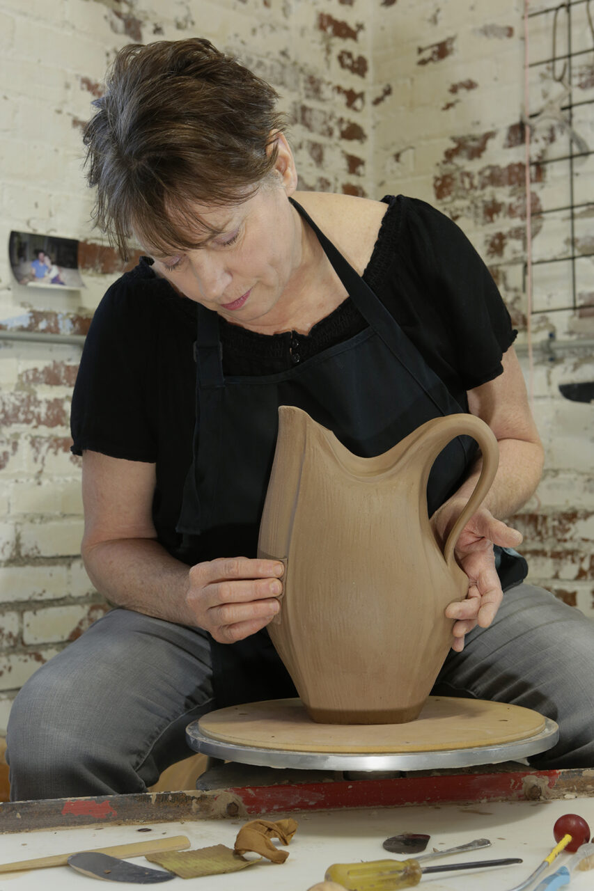 Sarah Wells Rolland sculpting shaping her signature closed form pitcher on potters wheel