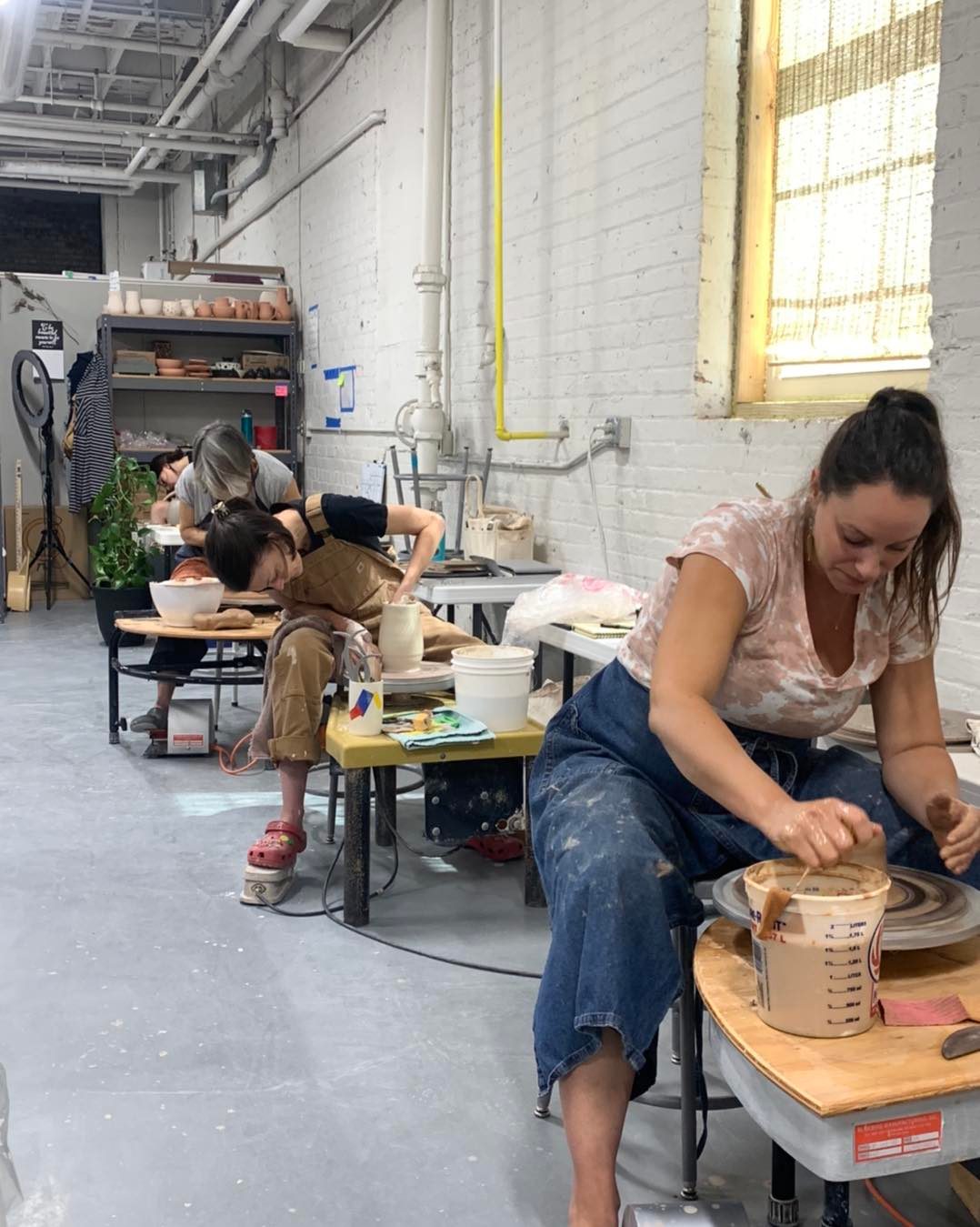 Students throwing at potters wheel in the hands on workshop classroom
