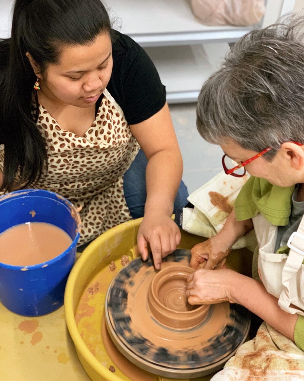 Katie Meili Messersmith teaching a student throwing on the potters wheel, TVP Teaching Center class