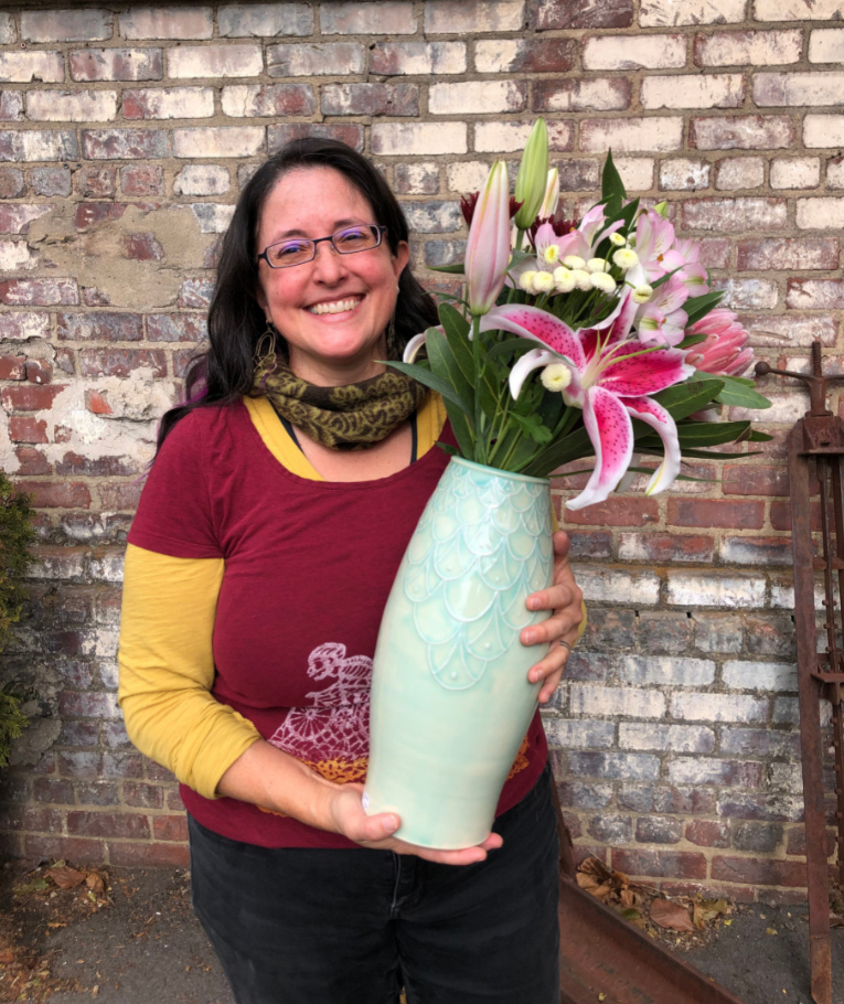 Maria Andrade Troya holding finished pot, vase with flowers