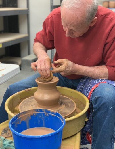 Teaching Center male student throwing on the potters wheel, beginning wheel class